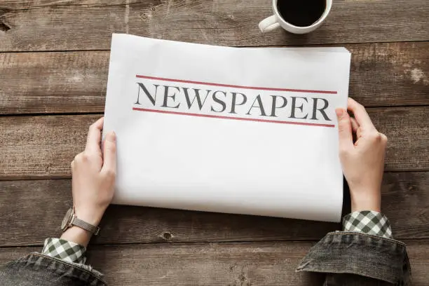 Photo of Woman reading newspaper on wooden background