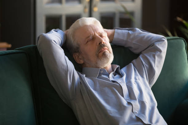 Sleeping grey haired man relaxing on comfortable sofa at home Sleeping middle aged man with closed eyes relaxing on comfortable sofa at home, grey haired carefree grandfather with hands behind head daydreaming, no stress peaceful free time at home close up sleeping grandpa stock pictures, royalty-free photos & images