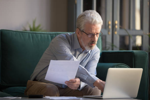 istock Grey haired mature man calculating bills, using laptop at home 1147376451
