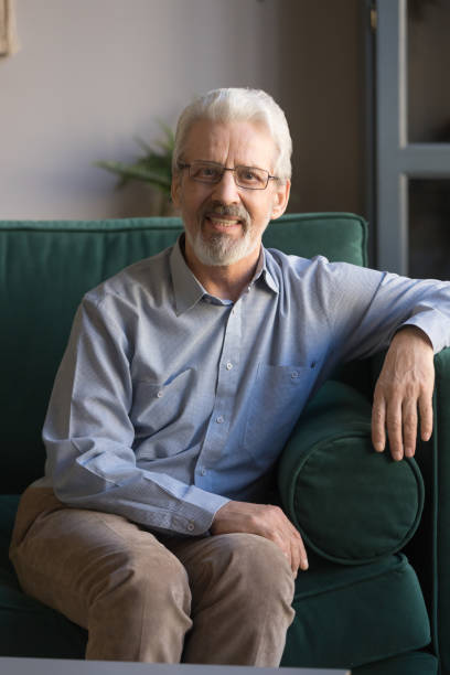 istock Vertical portrait of grey haired mature man sitting on couch 1147376465