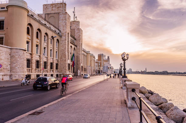 Bari, Italy - May 29, 2018 - Warm evening on the sea boarder, cars, scooters and bicycles driving the road next to big government building