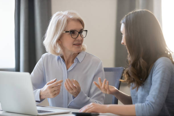 dipendenti di diverse età seduti alla scrivania che lavorano insieme per discutere del progetto - retirement senior adult planning finance foto e immagini stock