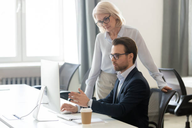 istock Aged female boss listens young manager asking about task 1147384799