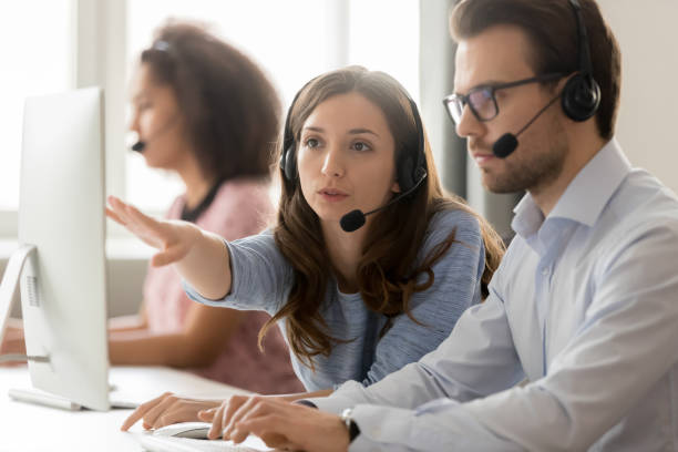 call center mujer trabajadora ayudando a hombre nuevo empleado colega - employee assistance program fotografías e imágenes de stock