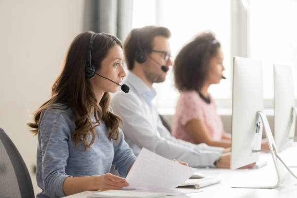 istock Call center worker holding paper talking with client use headset 1147384852