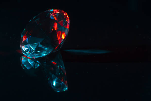 Closeup of a diamond on a black mirror surface with red and blue highlights, background or concept
