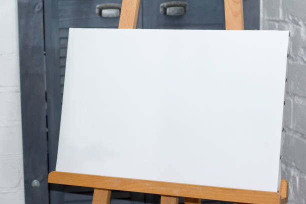 istock An easel with a clean white canvas is ready for work against a white brick wall, background or concept 1147386001
