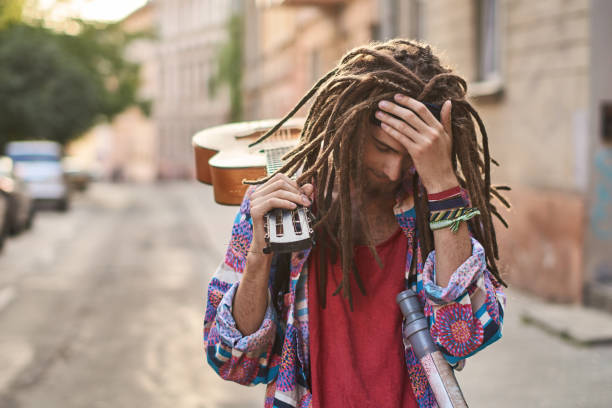 Young handsome bearded man hippie with dreadlocks looks depressed or dramatic stock photo