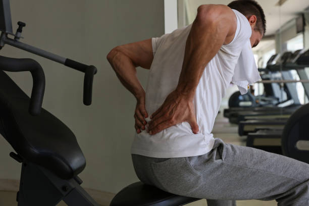 man with back pain in gym. sports exercising injury - lower back pain imagens e fotografias de stock