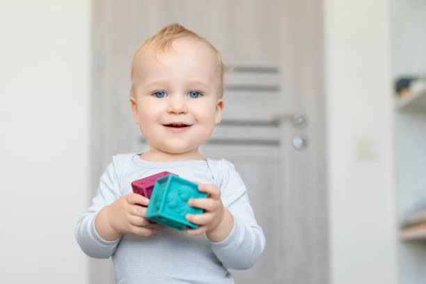 귀여운 사랑 스러운 백인 아기 소년 집에서 다채로운 장난감을 연주. 부드러운 고무 큐브의 재미 있는 건물 타워를 가진 행복 한 아이. 어린이 개발 및 하 피 칠리 후드 컨셉 - cube baby child block 뉴스 사진 이미지