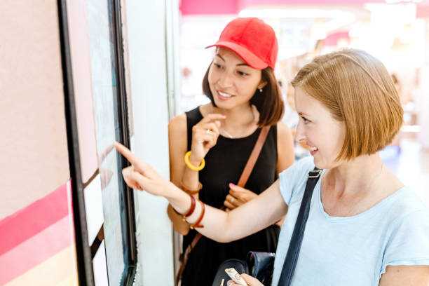 istock Two friends woman using automated self-service machine with big digital touch screen. Modern techmology concept 1147397661