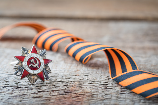 St. George ribbon and red carnation, may 9 Victory Day concept, symbol of the Second World war, dark wooden background, copy space
