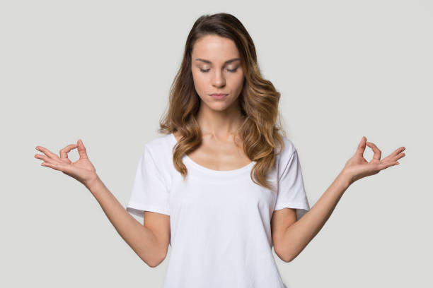 istock Young female closed eyes doing yoga over grey background 1147400429