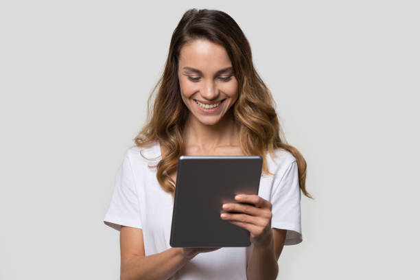 femme utilisant le gadget regardant le projectile de studio d’écran de tablette numérique - digital tablet women enjoyment happiness photos et images de collection