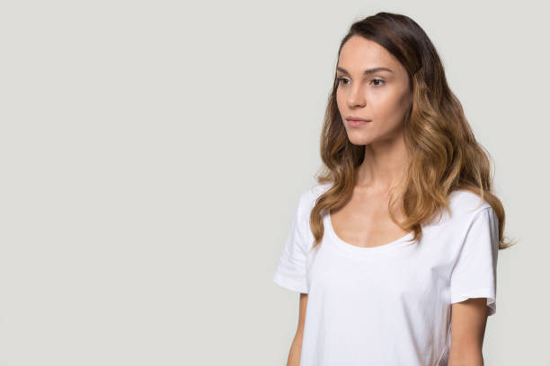 istock Serious attractive woman posing in studio aside over gray background 1147400496
