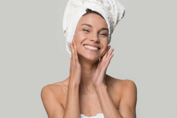 mujer sonriente con toalla en la cabeza toque la piel limpia y sana - facial massage human face women beauty fotografías e imágenes de stock