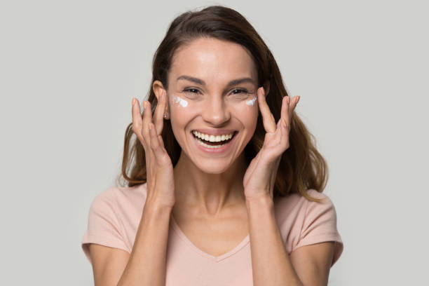 istock Happy woman looking at camera applying eyelid moisturizing cream 1147400547