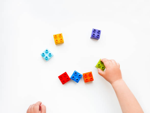 istock Child is playing with colorful constructor blocks. Kid's hands with bricks toy on white background. Educational toy, flat lay, top view. 1147401816