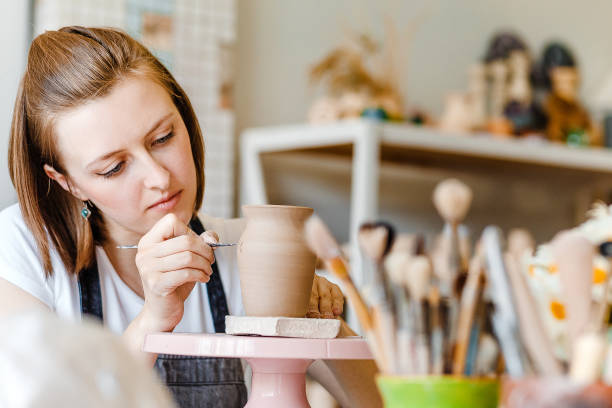istock Workshop of clay pottery ceramic, woman decorating dishware pot 1147402028