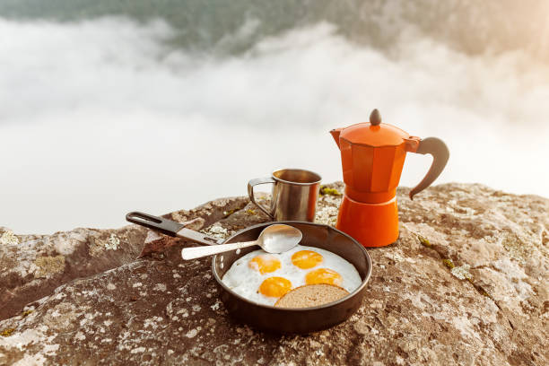 breakfast meal Fried eggs in pan and coffee geyser maker outdoors in mountains, camping food concept