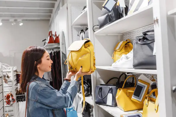 Photo of woman in shop choosing leather bags and backpacks, fashion accessories and shopping concept