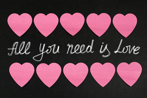 Paper hearts and text  All you need is love  on blackboard