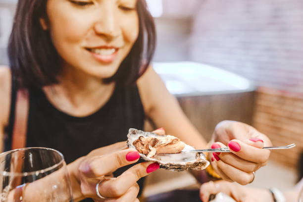 donna che mangia un'ostrica di prelibatezza, primo piano in un ristorante - oyster foto e immagini stock