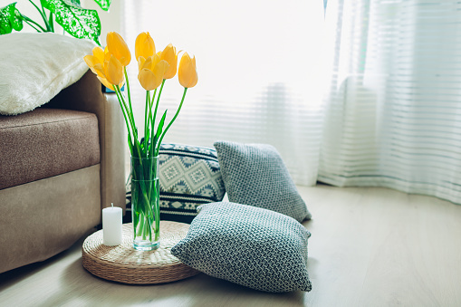 Details of modern living room interior. Tatami straw cushion decorated with flowers, candle and pillow on the floor