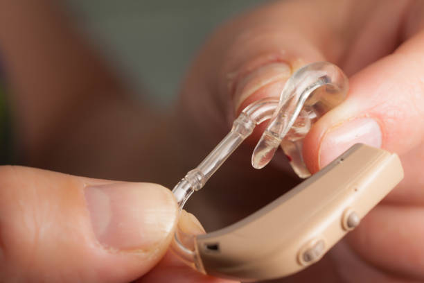 istock senior person holding hearing aid closeup 1147408754