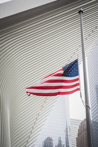 NEW YORK, USA - FEBRUARY 23, 2018: American flag floating under an architectural wing of the Oculus at the center of Wall Street in New York