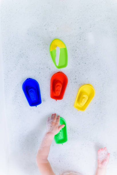 istock Plastic multicolored toy boats on foam bath. 1147412202