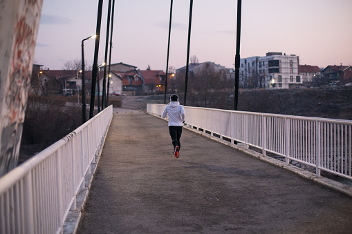 Young strong man exercising at sunrise in a city