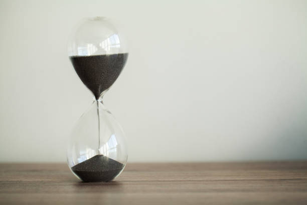 istock Time passing. A side view of an hourglass with falling sand 1147427718