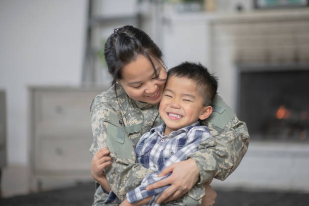 Military Mom Hugging Her Son A mother and her son are hugging in their living room. The mother is wearing a military uniform. filipino family reunion stock pictures, royalty-free photos & images