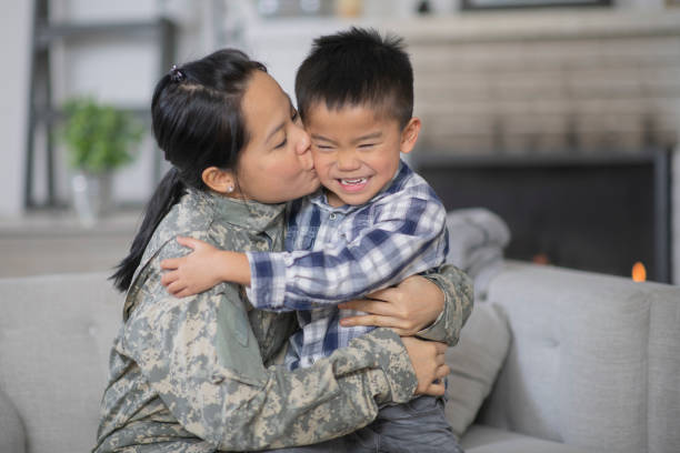 Military Mom Hugging Her Son A mother and her son are hugging in their living room. The mother is wearing a military uniform while the boy has a giant smile on his face. He is so excited that she is home. filipino family reunion stock pictures, royalty-free photos & images