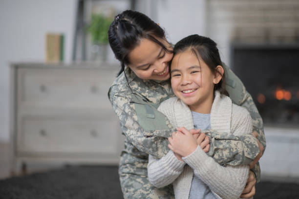 Happy Together A mother and daughter are hugging in their living room. The mother is wearing a military uniform. They are both excited that she is back from her deployment. filipino family reunion stock pictures, royalty-free photos & images