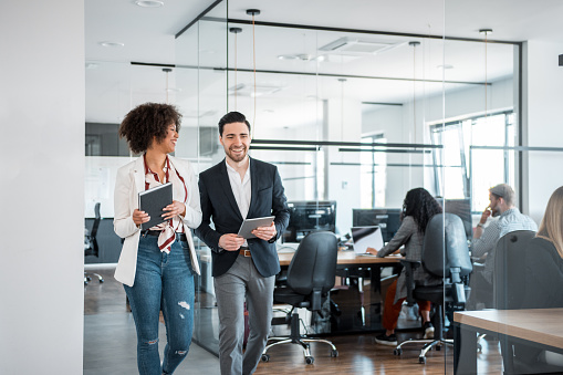 African businesswoman and her Caucasian coworkers using digital tablet and walking in the office