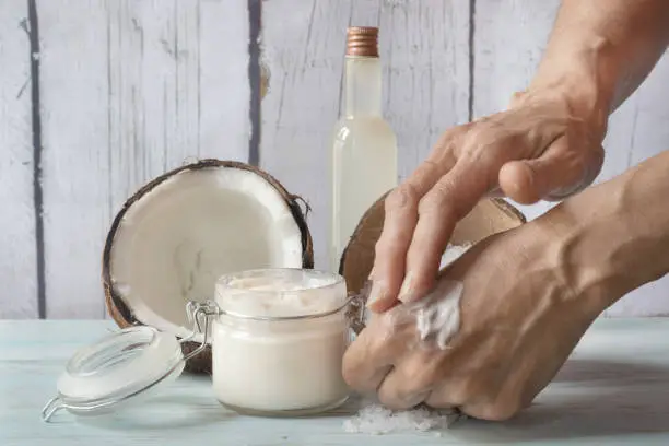 Human hands smearing cream. Homemade cream made of coconut and roses, in a glass jar