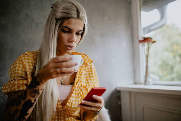 istock Young woman using smart phone and drinking coffee 1147433744