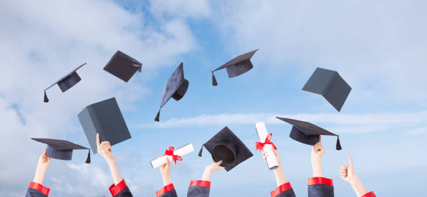 istock graduation ceremony hats  and hands up with sunny sky 1147436023