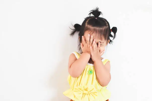 Photo of Cute asian baby girl closing her face and playing peekaboo or hide and seek with fun