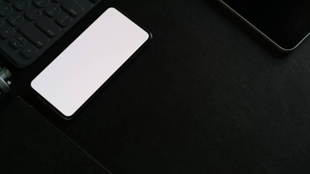 istock Mock up blank screen mobile phone and office accessory on dark office desk 1147443301