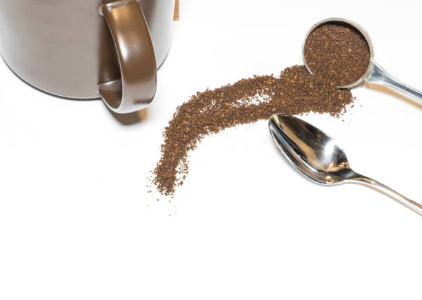 istock Coffee Grounds and Silver Spoon with Brown Mug Handle In on White Background 1147443405