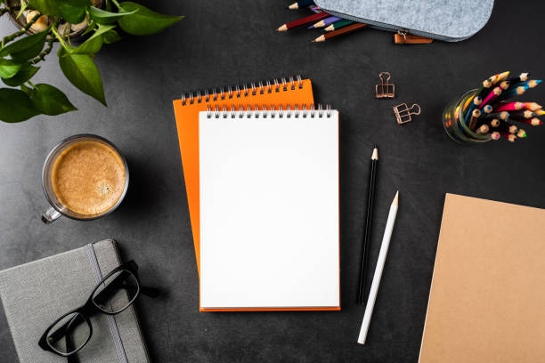 istock orange spiral notebook on black office background 1147445516