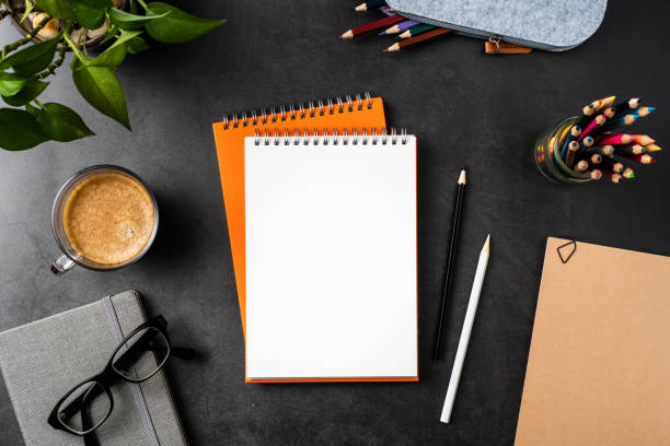 istock orange spiral notebook on black office background 1147445530