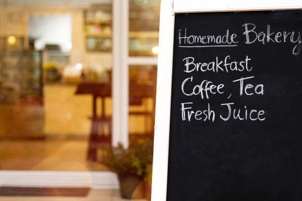 istock Close up beautiful hand writing menu on blackboard.Black chalk board in front of a coffee shop entrance.Blurred bakery and cafe background.Small business starting or shopping promotion concept. 1147446754