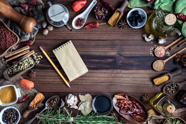 Variety of allspice ingredients and condiments for food seasoning around empty frame in old fashioned kitchen Variety of allspice ingredients and condiments for food seasoning on table in old fashioned kitchen. Ingredients set around empty frame with a notebook and pencil for recipes Cardamom stock pictures, royalty-free photos & images