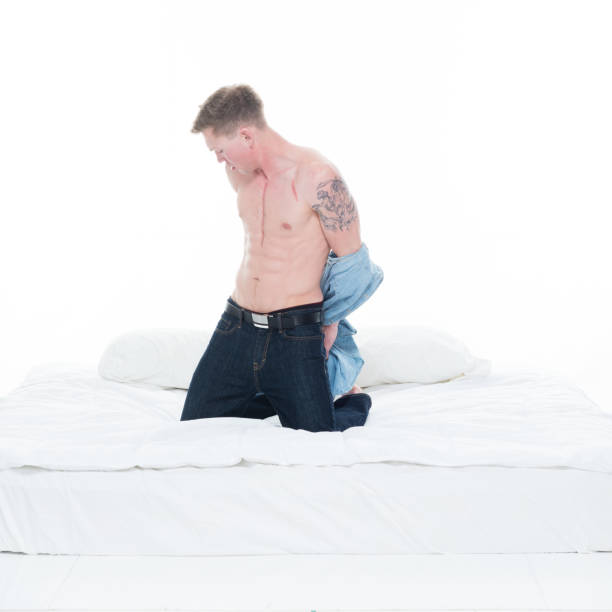 istock Sexy man undressing his shirt on a bed 1147452727