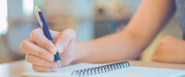 istock Woman hand is writing on a notepad with a pen in office. 1147454075