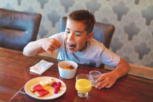 istock Mixed Ethnic Young Boy Eating Breakfast Cereal with Healthy Fruit and Milk 1147454138